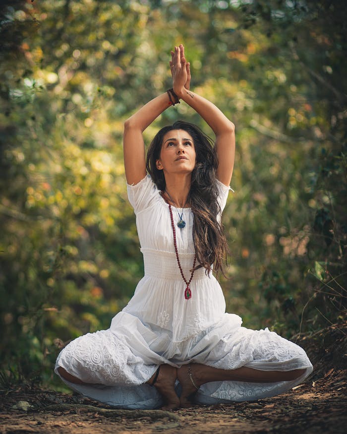 about-us A woman meditating outdoors in a forest setting, embracing tranquility.